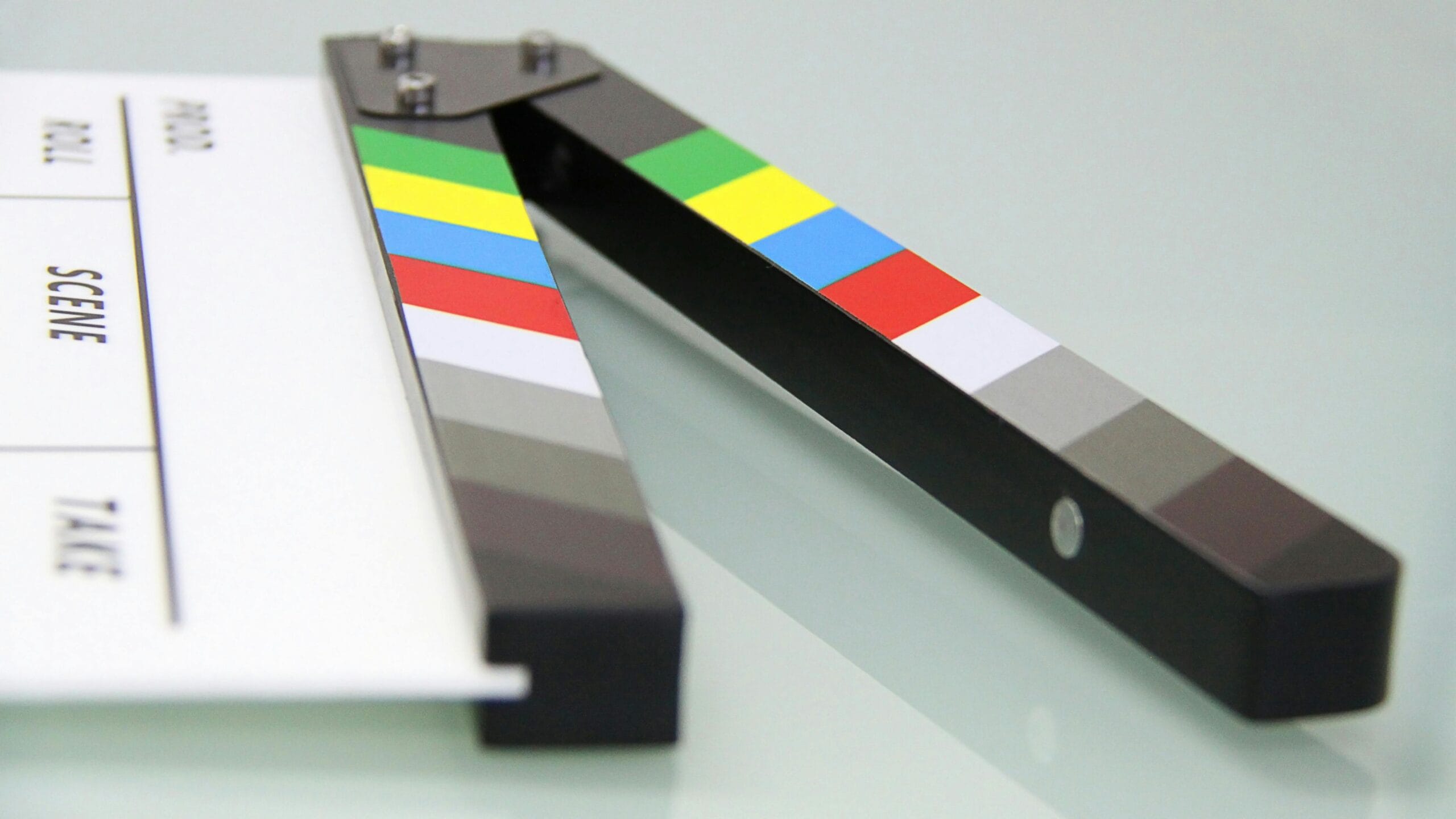 Strona Główna Colorful clapper board on a white surface, used in filmmaking. Ideal for entertainment and movie themes.